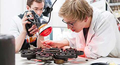 Zwei Studenten bearbeiten ein technisches Objekt in einem Labor